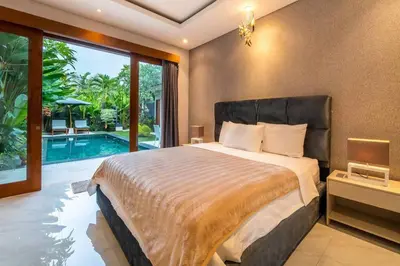 a bedroom with a large bed and a swimming pool at Cozy villa in Umalas in Kerobokan