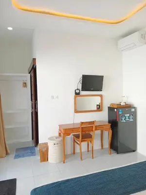 a room with a wooden table and a small refrigerator at Double D Guesthouse and Villa in Kerobokan