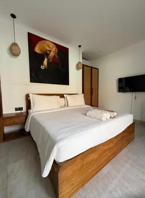 a bedroom with a large bed with a painting on the wall at New 2BR Villa Private Pool Near Seminyak in Kerobokan