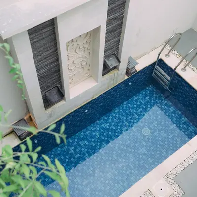 a swimming pool in a house with a blue tile floor at The Lavana Nakula Villa Kuta Sunset in Kuta