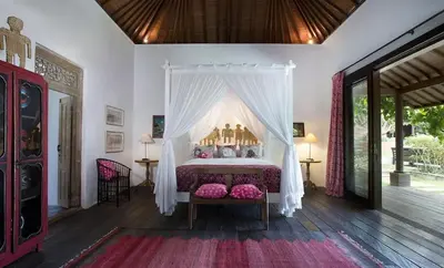 a bedroom with a canopy bed with pink pillows at Villa Mamoune in Canggu