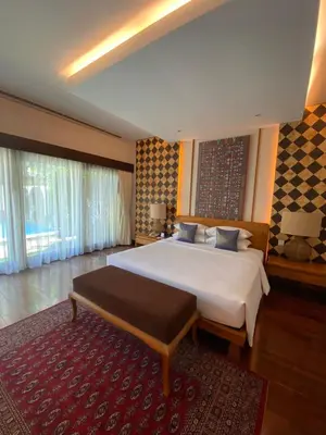 a bedroom with a large white bed and a red rug at Bintang Bali Villa in Kuta