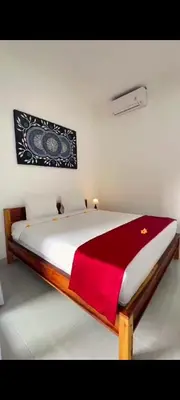 a bedroom with a bed with a red blanket on it at narayuka house in Seminyak
