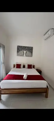 a bedroom with a large bed with red pillows at narayuka house in Seminyak
