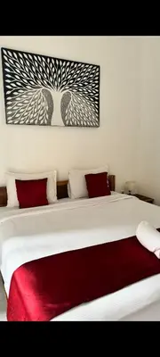 a bedroom with a large white bed with red pillows at narayuka house in Seminyak