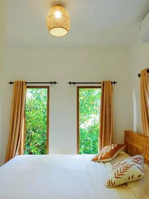 a bedroom with a large bed and two windows at Vee Surf in Canggu