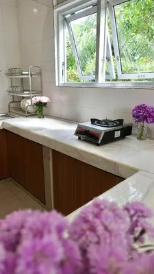 a kitchen with a sink and a window and purple flowers at Vee Surf in Canggu