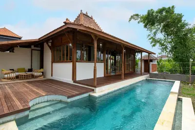 a villa with a swimming pool and a house at Sunset Joglo Pool Villa in Kerobokan