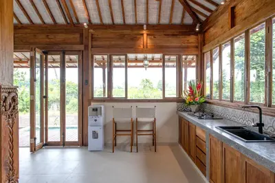 a kitchen with wooden walls and windows and a counter at Sunset Joglo Pool Villa in Kerobokan