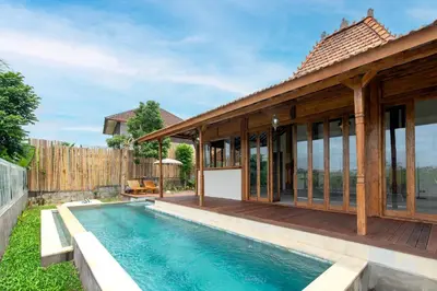 a house with a swimming pool and a deck at Sunset Joglo Pool Villa in Kerobokan
