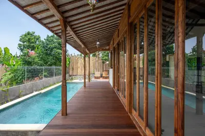 a wooden walkway leading to a pool in a house at Sunset Joglo Pool Villa in Kerobokan