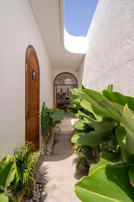 a hallway with plants and a wooden door at Sueño Villa Seminyak in Seminyak