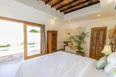 a bedroom with a white bed and a large window at Villa Jannu by DreamAwayBali in Seminyak