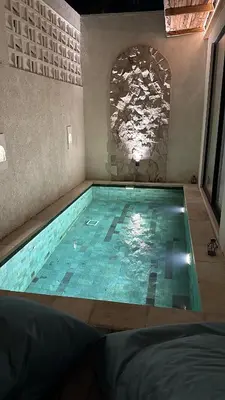 a swimming pool in a room with a stone wall at Balimac Villa 3 in Seminyak
