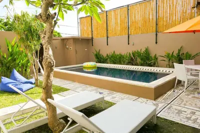 a swimming pool with two chairs and an umbrella at Family Villa with Private Pool in Central Seminyak in Seminyak