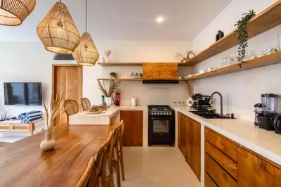 a kitchen with a wooden counter top and wooden tables at Wayang Villa by Betterplace in Kerobokan