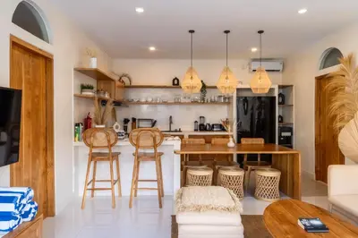 a kitchen with a bar with stools and a table at Wayang Villa by Betterplace in Kerobokan