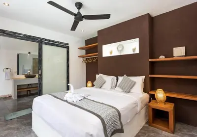 a bedroom with a large bed with a ceiling fan at Villa Julietta, 4 BR in the heart of Seminyak in Seminyak