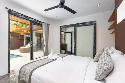 a bedroom with a white bed with a ceiling fan at Villa Julietta, 4 BR in the heart of Seminyak in Seminyak