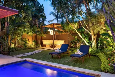 a backyard with a swimming pool and two blue chairs at Villa Julietta, 4 BR in the heart of Seminyak in Seminyak