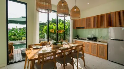 a kitchen with a table with chairs and a refrigerator at Sunset D1 Villa by Betterplace in Kerobokan