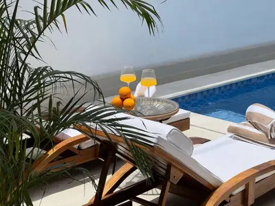 a table and chairs with wine glasses and a swimming pool at LUX 3 Bedroom Villa 5min Walk to the Beach in Canggu