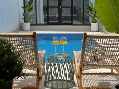two wine glasses sitting on a table next to a pool at Nomadic LUX villa in Canggu