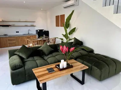 a living room with a green couch and a table at LUX Villa, Private Pool Berawa in Canggu