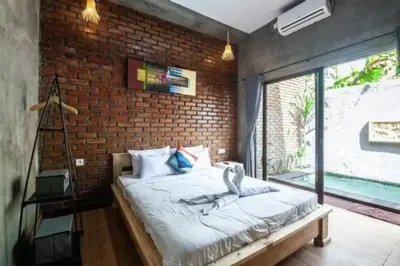 a bedroom with a brick wall and a bed at Mantra Guesthouse in Denpasar