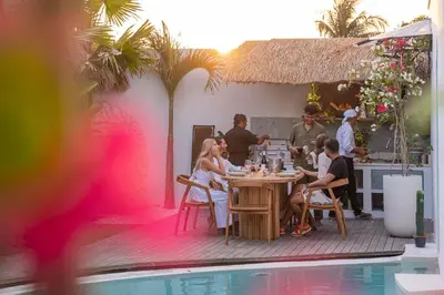 a group of people sitting at a table by a pool at Luxury 4BD Villa Casa Diplomatico with Private Pool in Seminyak