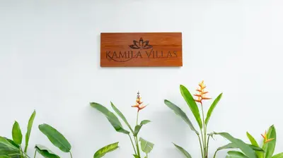 a sign on a wall next to two plants at Kamila Villa 2 by Villa Finder in Seminyak