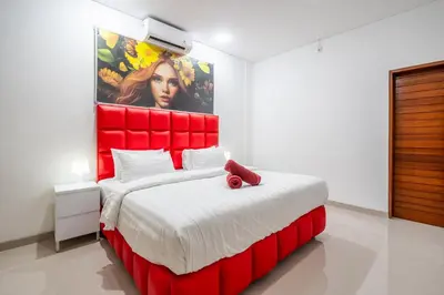 a bedroom with a red bed with a painting on the wall at Brand new luxury minimalistic villa The Toy with 3 bedrooms in Kerobokan