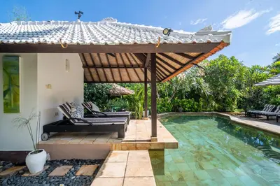 an outdoor patio with a pool and a pergola at Villa Nyumpene in Legian in Legian