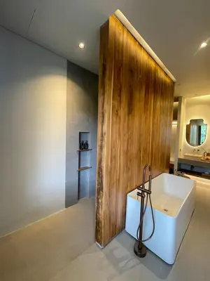 a bathroom with a white tub and a wooden wall at Villa Gabrielle in Seminyak
