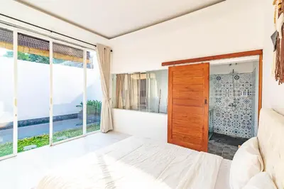 a bedroom with a bed and large windows at Cendani Private Pool Villa Bali in Kuta