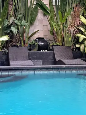 two chairs sitting next to a swimming pool at SURFARIS INN on poppies 2 apartment in Legian