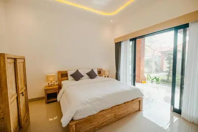 a bedroom with a bed and a large window at Kubu Dangin Guest House Kerobokan in Seminyak