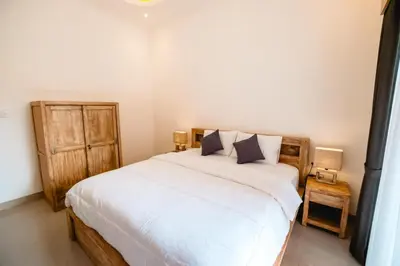 a bedroom with a large white bed with two lamps at Kubu Dangin Guest House Kerobokan in Seminyak