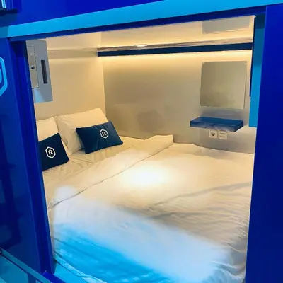 two twin beds in a room with blue lights at Rosalyne Sleepbox Denpasar Bali in Seminyak