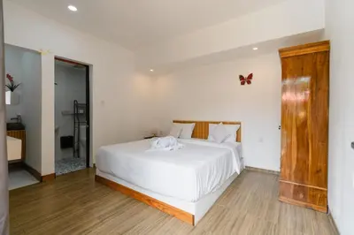 a bedroom with a white bed with a butterfly on the wall at Griya Sadhana Dewi Sri in Legian