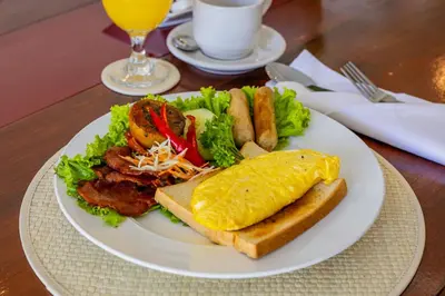 a white plate of food with a sandwich and a egg and bacon at Villa Isabella in Seminyak