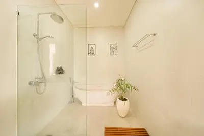 a bathroom with a tub and a shower and a plant at Shanti Villa - 3BR Luxury Private Pool Villa in Seminyak in Seminyak