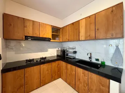 a kitchen with wooden cabinets and a black counter top at Solvana Villas Sanur by AGATA in Sanur
