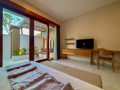 a bedroom with a bed and a desk with a television at Solvana Villas Sanur by AGATA in Sanur