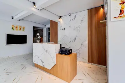 a lobby with a counter with a tv on a marble wall at Townhouse Oak Legian Near Legian Beach Formerly Sayang Maha Merta in Legian
