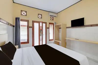 a bedroom with a bed and a flat screen tv at Townhouse Oak Legian Near Legian Beach Formerly Sayang Maha Merta in Legian