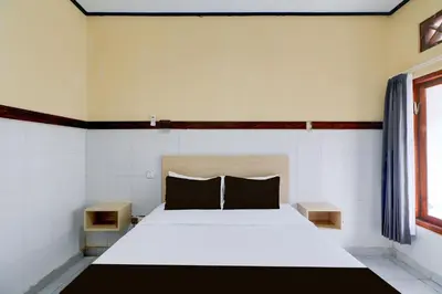 a bedroom with a white bed with two night stands at Townhouse Oak Legian Near Legian Beach Formerly Sayang Maha Merta in Legian