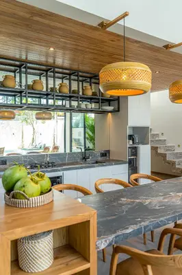 a kitchen with a wooden table and chairs at Villa Bayu by GORO in Canggu