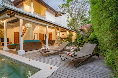 a patio with two lounge chairs and a swimming pool at Villa Shanti Seminyak in Seminyak