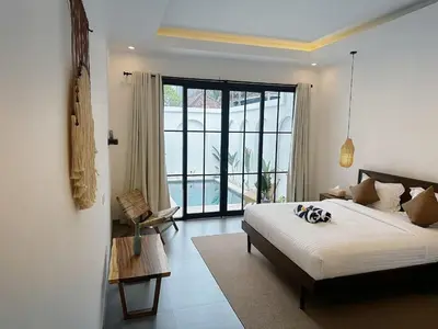 a bedroom with a bed and a large window at Kamila Villas 2BR Private Pool Seminyak Central in Seminyak